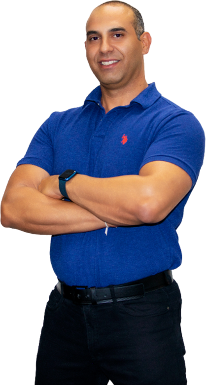 Smiling sports chiropractor, Dr. Roy Nissim, confidently crossing arms in a blue polo shirt