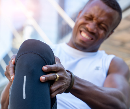 a runner holding his knee in pain