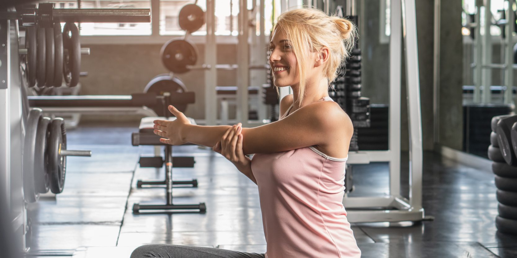 woman stretching shoulders muscle before workout in gym.