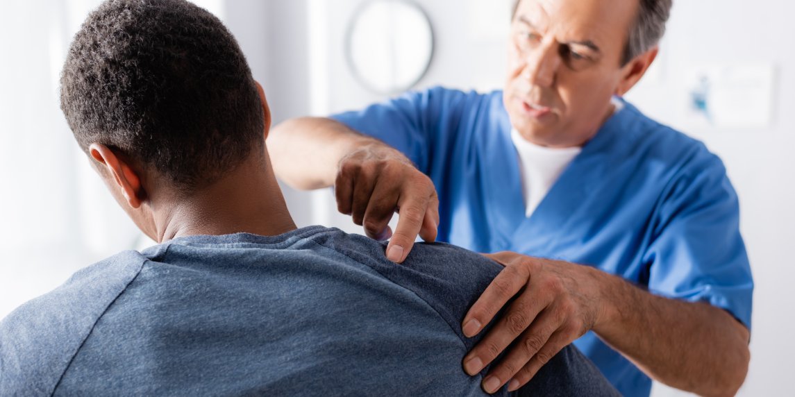 blurred chiropractor working with african american man in clinic