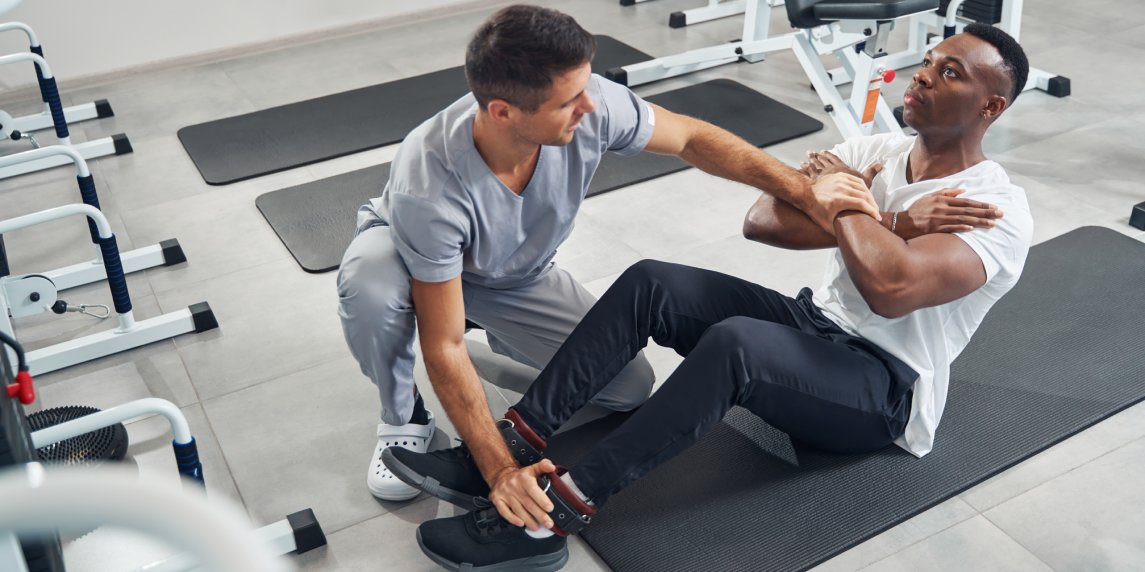 Certified physical therapist checking muscle strength of young man