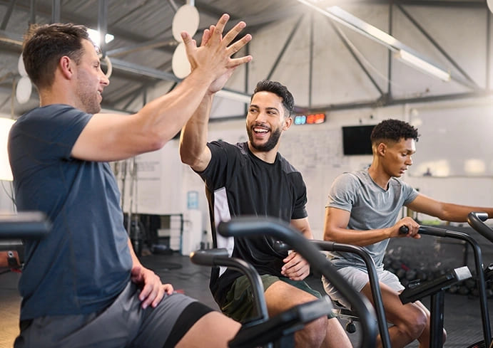Sports Medicine in Santa Monica : Three men in a gym celebrating their workout with high fives, showcasing teamwork and motivation in sports medicine.