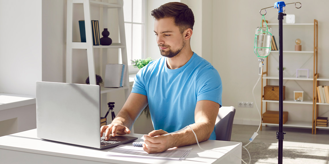A man at a desk using a laptop, exploring IV therapy options for immune support in a professional environment.