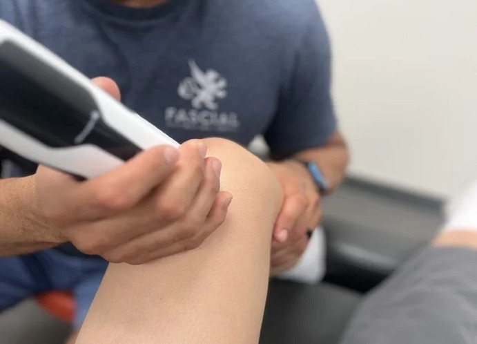 Shockwave therapy in Santa Monica: Patient experiencing machine-assisted shockwave therapy targeting the knee area for therapeutic treatment at Dr Roy Nissim Santa Monica