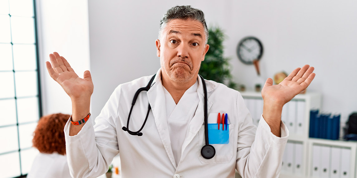 A man in a white coat stands by a desk, illustrating key points about choosing a chiropractor.
