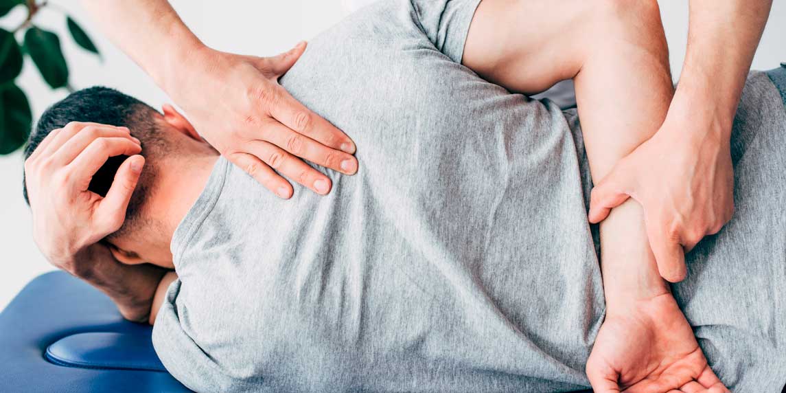 Back view of chiropractor massaging back of man lying on Massage Table in hospital