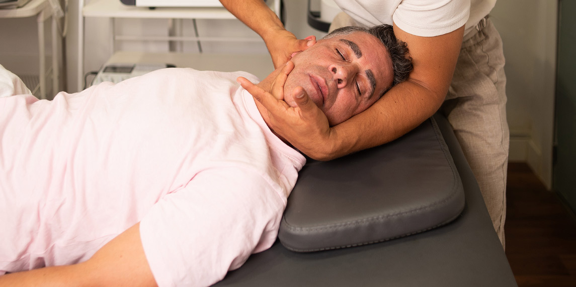 Professional young chiropractor helping get rid of neck pain to young man patient