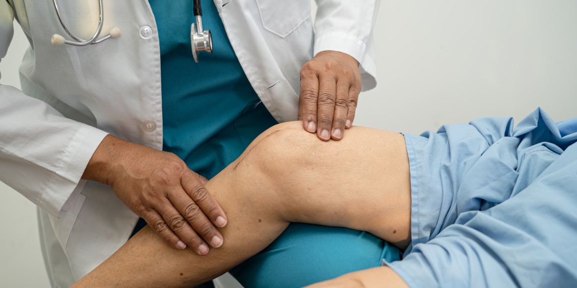 Asian doctor physiotherapist examining, massaging and treatment knee and leg of senior patient in orthopedist medical clinic nurse hospital.