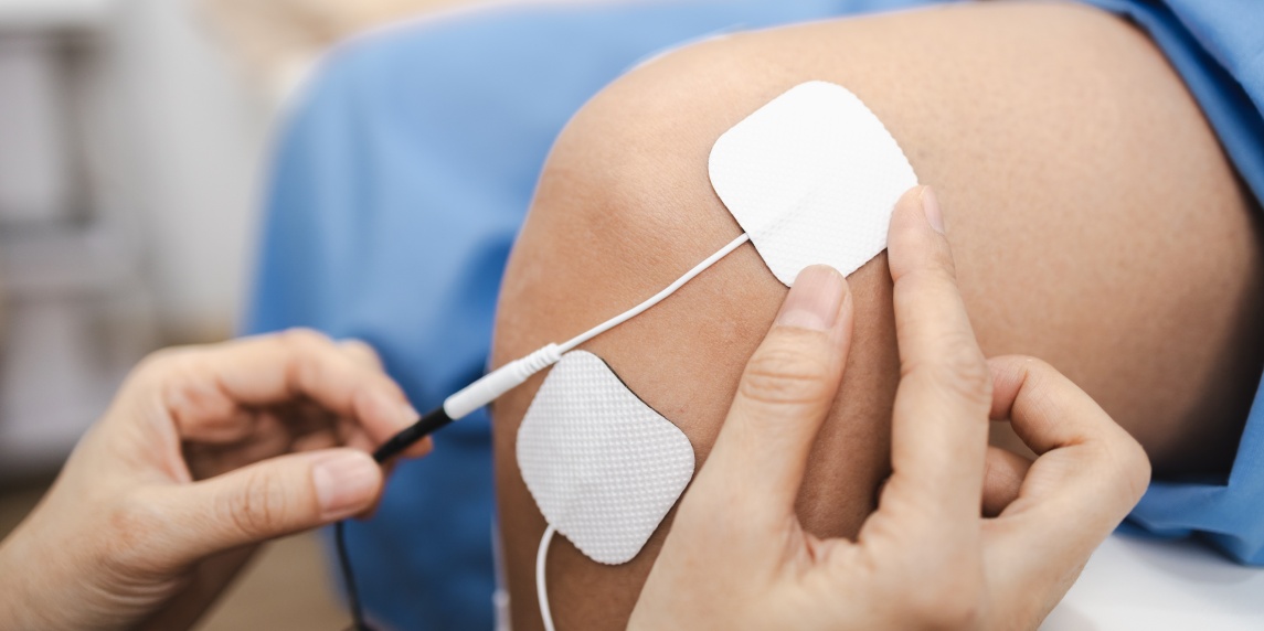An image depicts person receiving electrical stimulation therapy their knee, showcasing application of physical therapy techniques for pain relief
