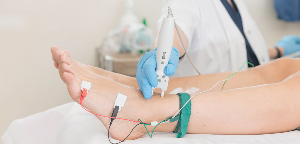 In a clinical room, a healthcare professional performs electromyography testing on a patient's leg. This procedure checks nerve function and muscle response, aiding in diagnostics